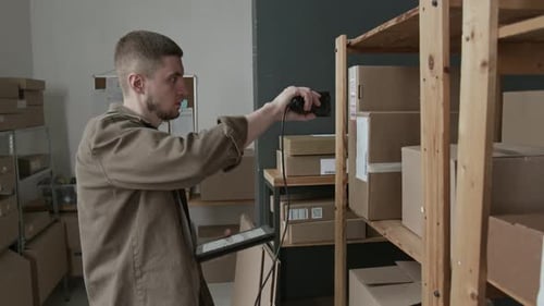 Storehouse Worker Scanning Barcodes on Cardboard Boxes with Reader Device