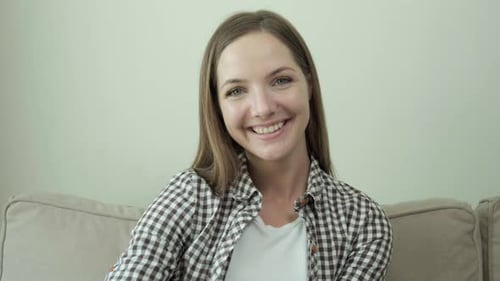 Happy Woman Waving and Smiling on Couch