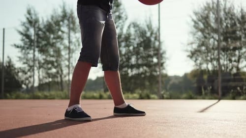 Homme caucasien dribble au basket sur un terrain extérieur moderne par une journée ensoleillée
