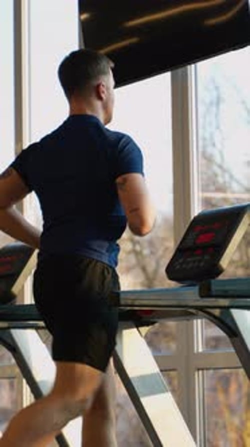Man Jogging on Treadmill in Sunny Gym