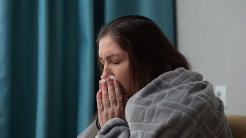 Une femme adulte recouverte d'une couverture ne se sent pas bien dans une maison froide