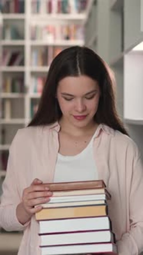 Young Woman Holds Books in University Library