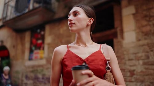 Woman Walking in European City with Coffee