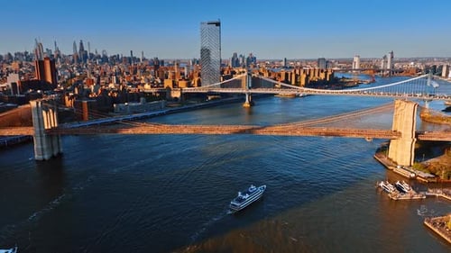 Warm light of setting sun on the bridges over the East River and facades of New York buildings