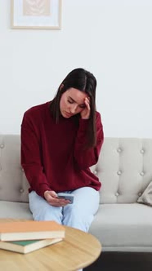 Young Woman Feeling Sad While Using Smartphone at Home