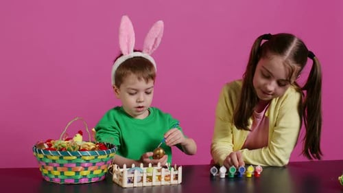 Enfants enjoués peignant des œufs à l'aquarelle et à des Pinceaux
