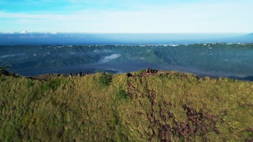 Vaste paysage volcanique avec des randonneurs surplombant la caldeira du mont Batur au lever du soleil (images aériennes)