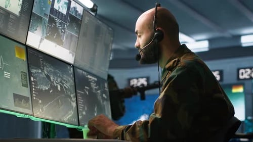 Man Monitors Bank of Computer Screens in Control Room