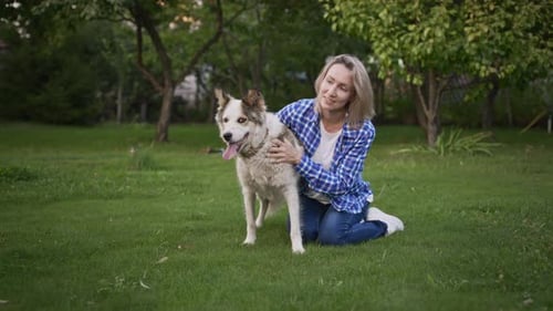 Young Woman in the Garden with Her Dog The Owner Loves Her Pet and is Happy to Spend Time with Him