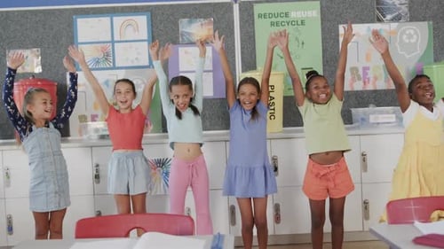 Portrait of happy diverse schoolgirls raising hands in elementary school classroom in slow motion