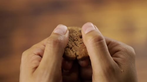 Hands Break a Chocolate Chip Cookie in Half