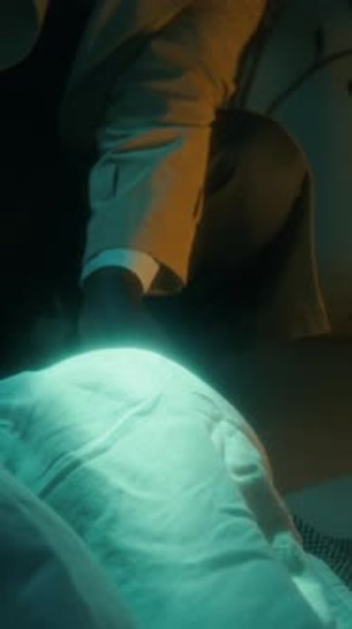 Detective Inspecting Covered Body in Dark Setting