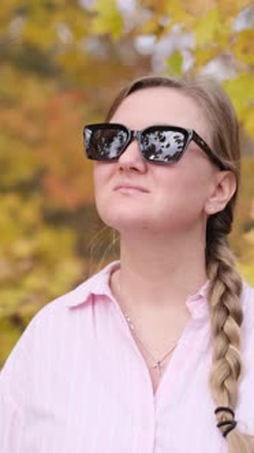 Woman Wearing Sunglasses Posing in Front of Fall Leaves