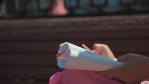 Woman Holds Open Notebook on Sunny Park Bench
