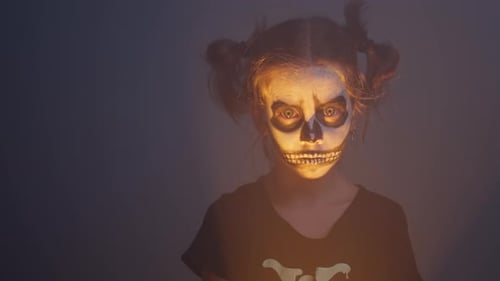 Girl with Skull Face Paint and Spooky Makeup Holding Torch in Dark Room
