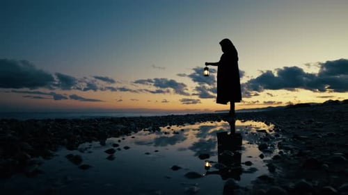 Silhouette with Lantern on Beach at Sunset
