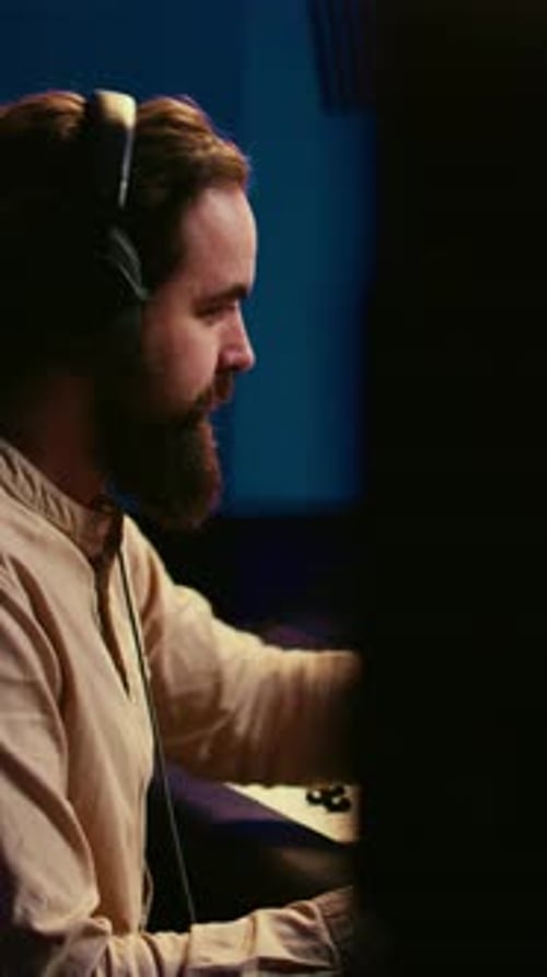 Man Adjusting Mixing Board in Dark Music Studio