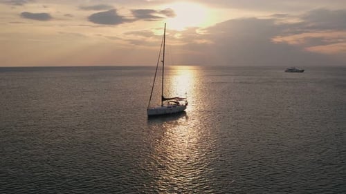 Sailboat Glides Across Water at Sunset