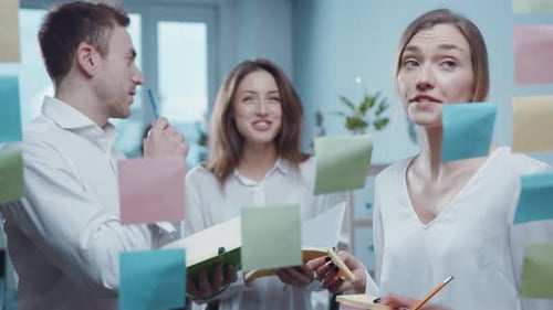 Team Brainstorming Ideas Using Sticky Notes on Glass