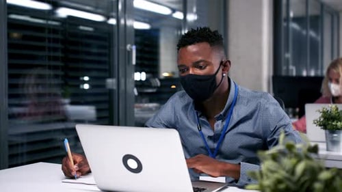 African-American Businessman with Face Mask Indoors in Office at Night, Coronavirus Concept