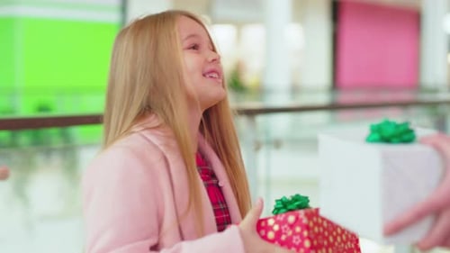 Close Up Father and His Daughter Exchanging Christmas Present Boxes Gifts on Shopping Center Talk