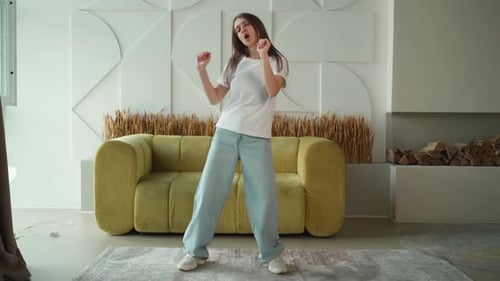 Happy Joyful Young Woman in a Positive Mood is Dancing Rhythmically Moving and Jumping Listening to