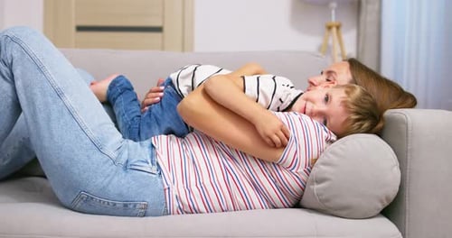Woman and Child Cuddling on Sofa