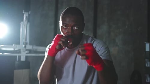 Workout in Gym African Man Fighter Ready for Fight Punching with Boxing Wraps Protective Bandages to