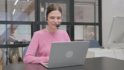 Young Woman with Headset Talking Online with Customer in Call Center