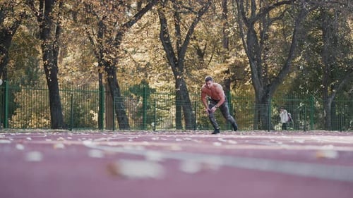 Muscular man is training on outdoor stadium.