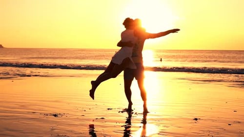 Happy young couple turning around on beach during golden sunset in super slow motion