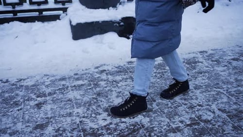 Woman Carefully Walking on Icy Sidewalk in Winter