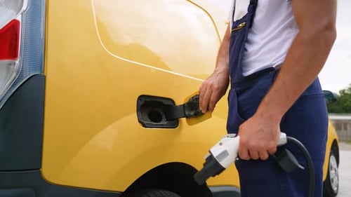 Man Plugs Electric Vehicle Charger into Yellow Van