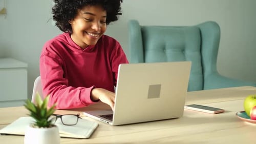 African American Girl Using Laptop at Home Office Looking at Screen Typing Chatting Reading Writing