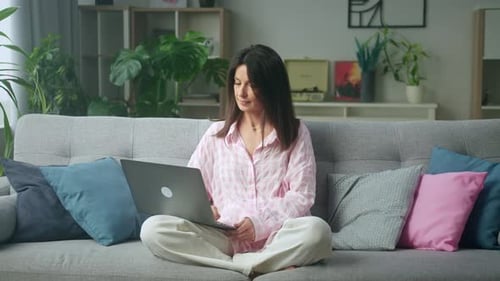 Woman Working on Laptop on Couch at Home