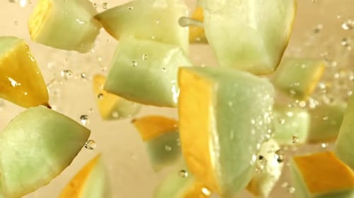 Des morceaux de melon volent sur un fond clair filmés par une caméra à haute vitesse à 1000 images par seconde