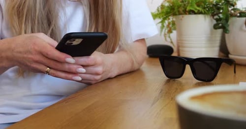 Woman Uses Mobile Phone at Table Indoors