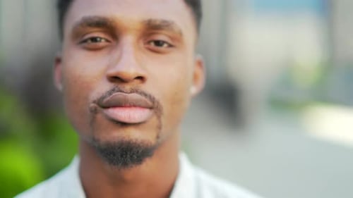 close up portrait serious African American man looking at camera outside. Face of confident young