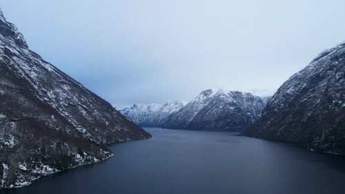Scenic drone shot of Sunnylvsfjord, a fjord in Norway with tall mountains and steep cliffs and snow