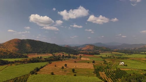 aerial drone view captures wide valley with mountain ranges and agricultural farmland under blue sky