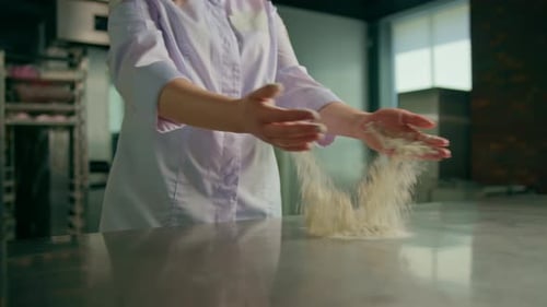 An experienced chef applies flour to his hands before making bread in a bakery prepares pastries
