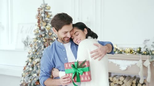 Happy couple hugging while standing in living room at home during winter New Year Christmas Xmas