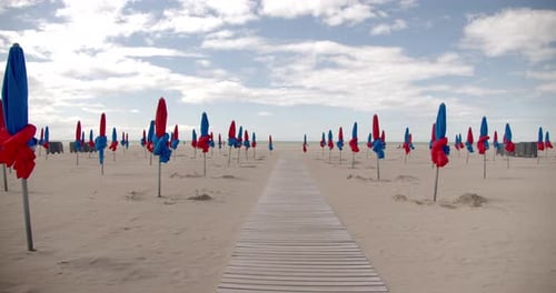 Closed beach umbrellas on an empty beach with walkway. Vacation holiday relaxation concept