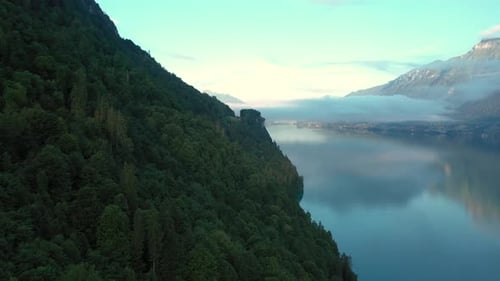 Drone flight over a beautiful Swiss alpine lake. The drone flies above the valley forest to reveal t