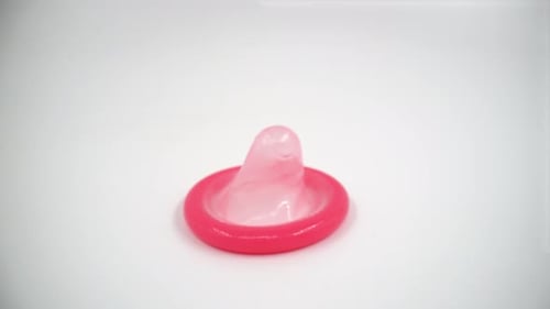 Bright Pink Condom on a White Background