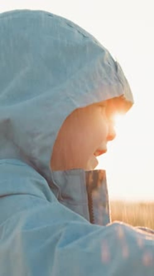 Smiling Child in Rain During Golden Hour