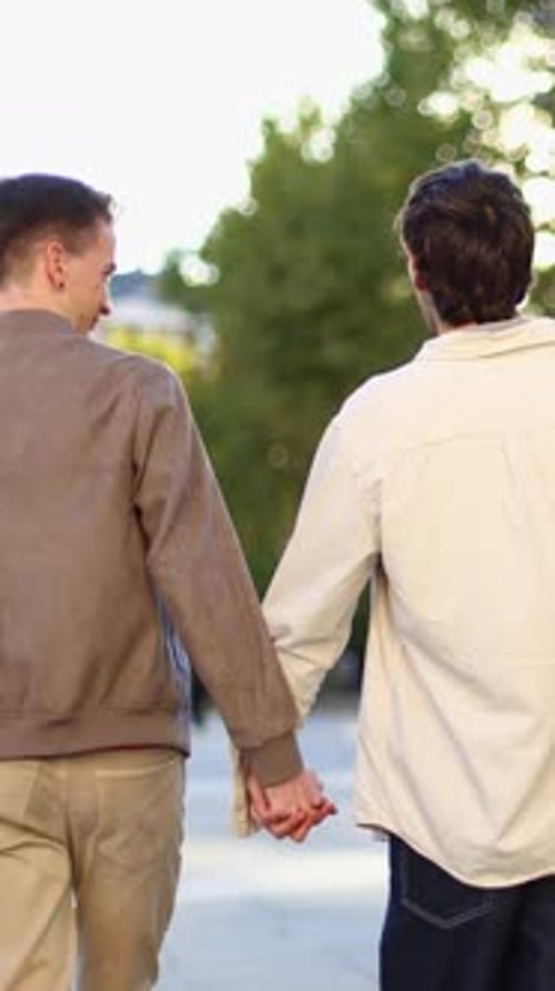 Couple Holds Hands Walking Together in Urban Park