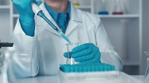 Female Scientist Pipetting Blue Liquid in Laboratory