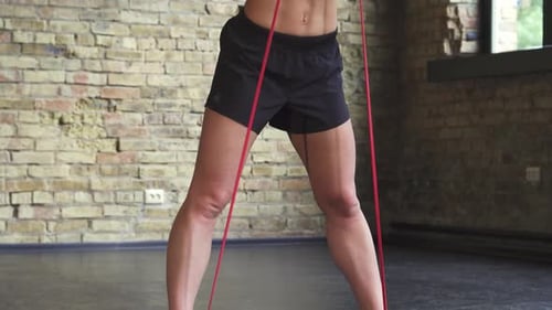 Athletic Woman Exercising with Resistance Band in Gym
