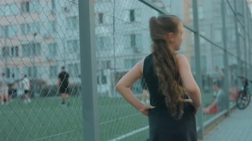 Happy Blonde School Girl Standing Near a Football Stadium and Watching the Game Spinnig to Camera